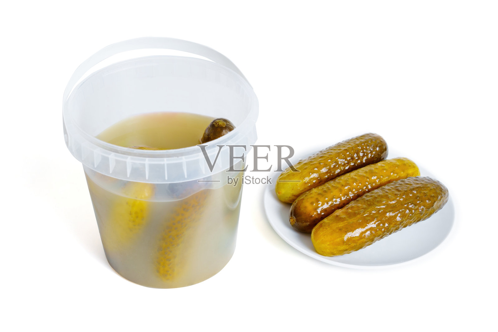 盘子里有三个腌黄瓜，旁边有一个桶照片摄影图片