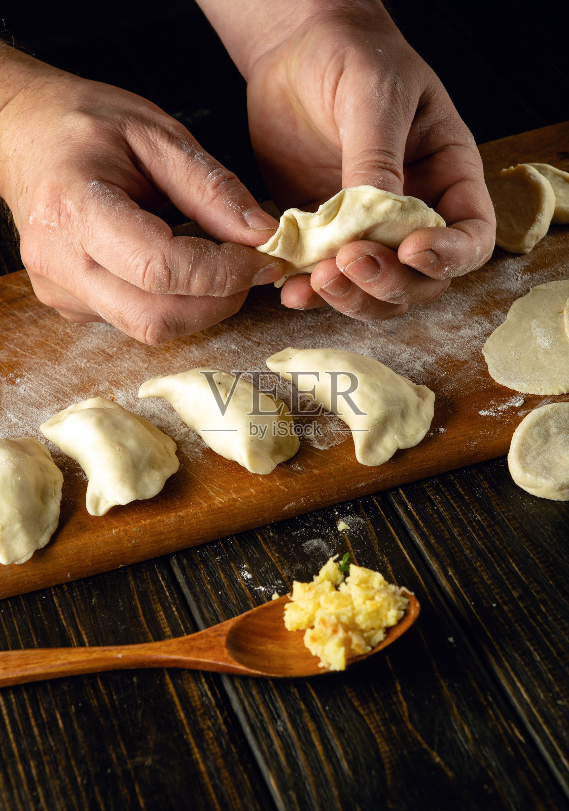 厨师用手把面团和土豆做成饺子。在餐桌上准备美味饺子的概念照片摄影图片