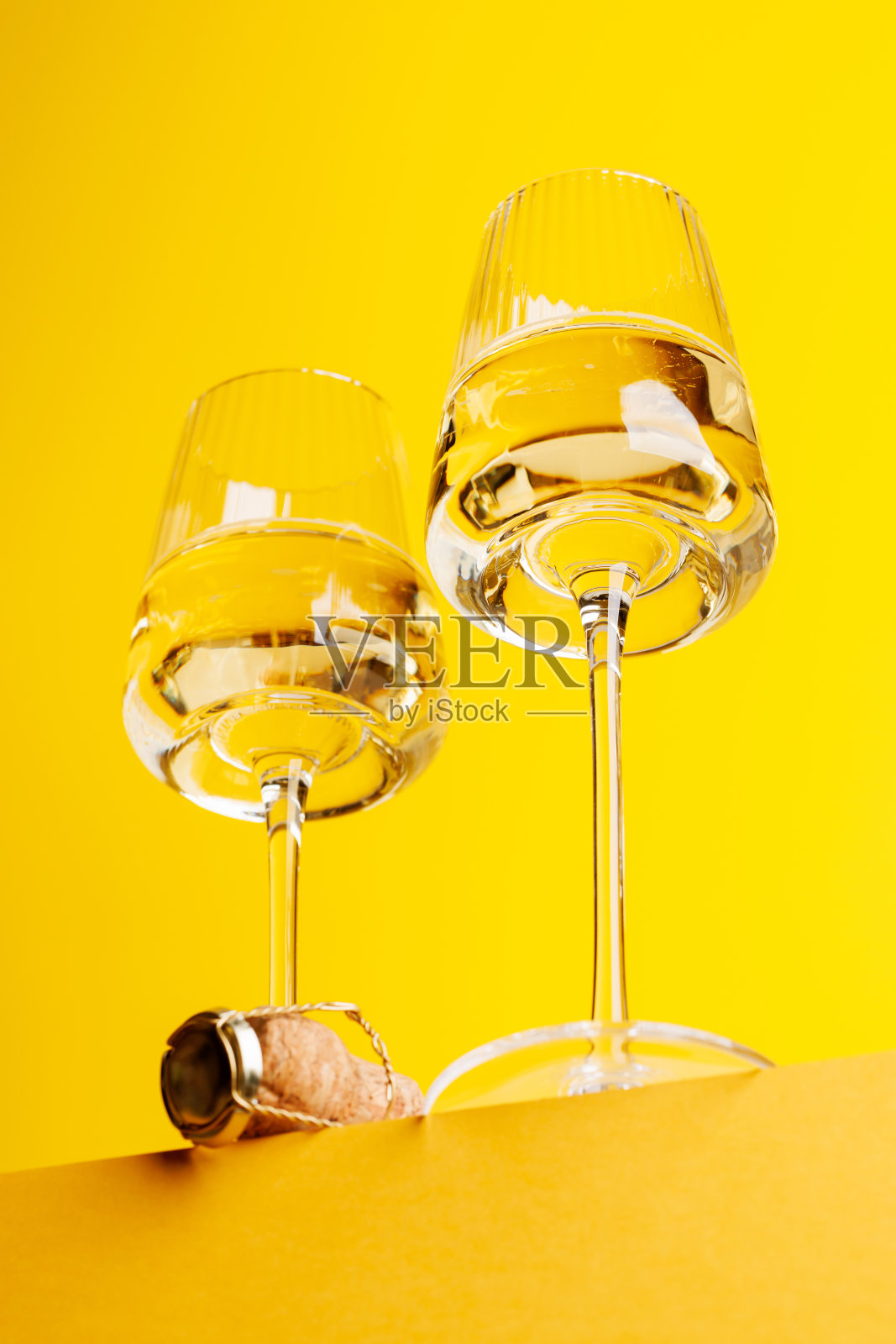 优雅的香槟:在充满活力的黄色背景下，配上气泡酒的酒杯照片摄影图片