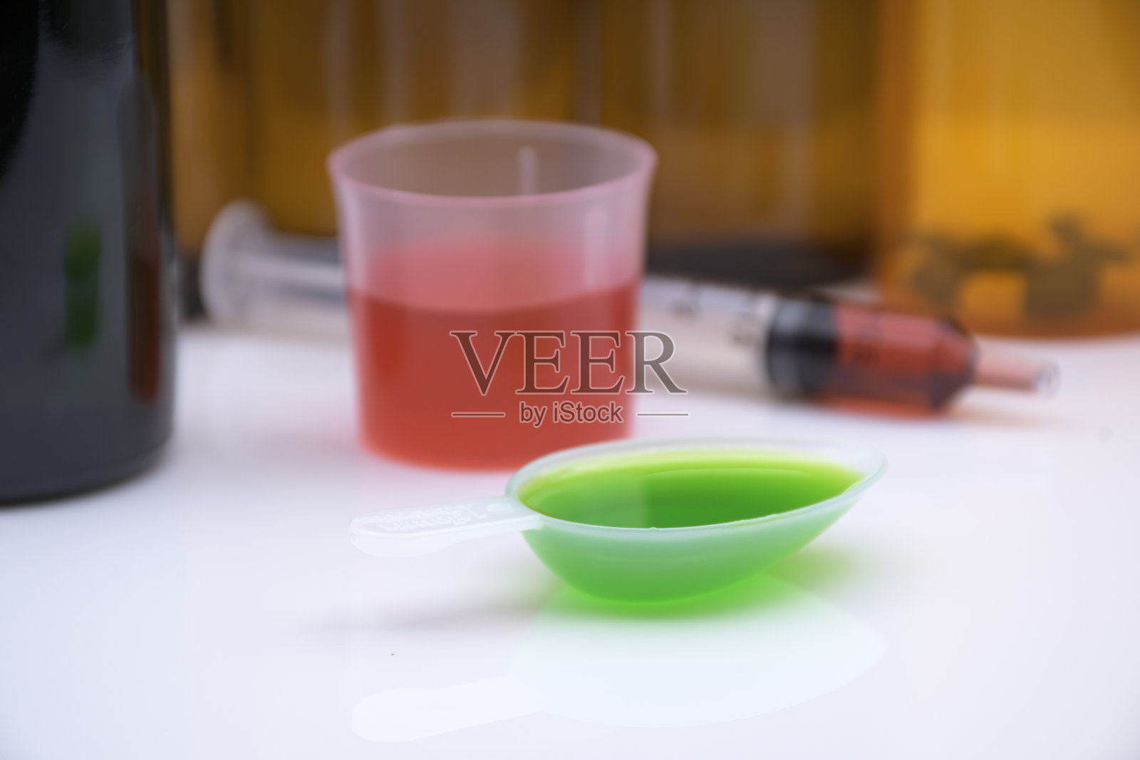白底糖浆药瓶，药杯，药匙和药物口服注射器。照片摄影图片