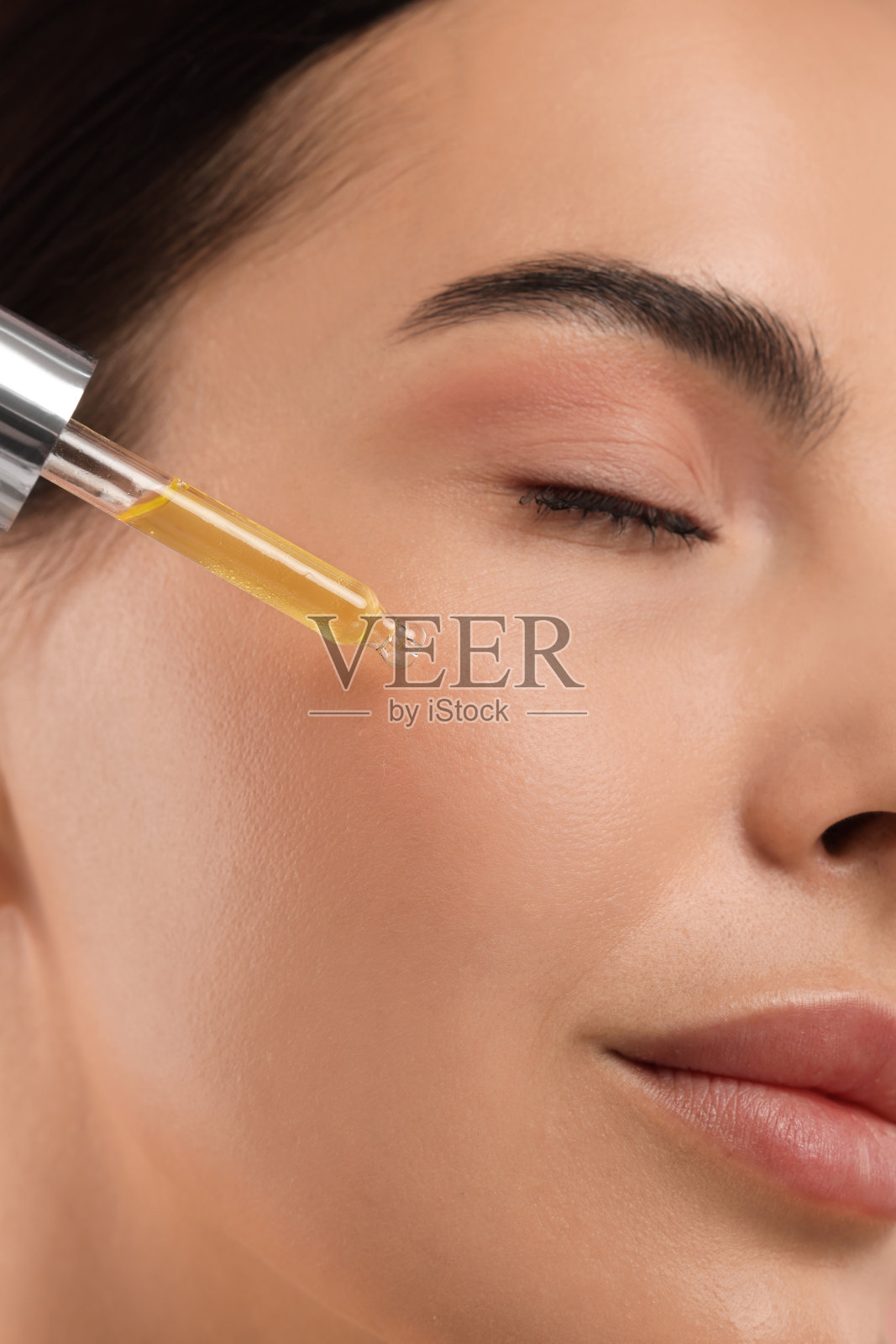 美丽的年轻女子在脸上涂抹精华液，特写照片摄影图片