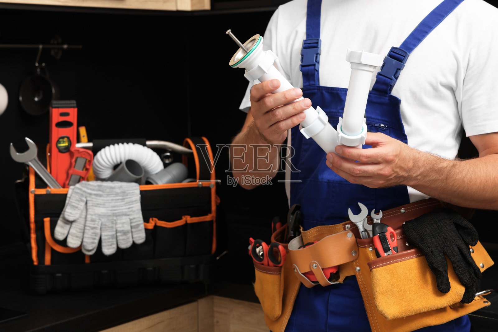 专业水管工与波纹管和工具带在室内，特写照片摄影图片