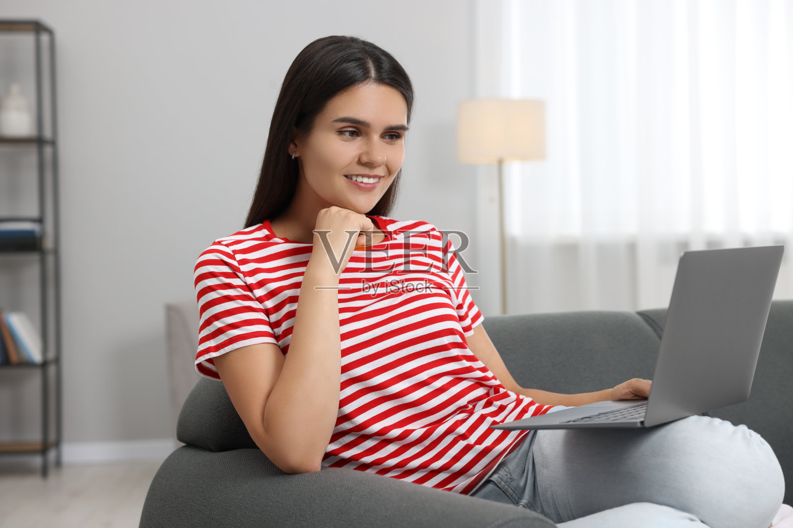 快乐的年轻女子在客厅的沙发上通过笔记本电脑视频聊天照片摄影图片