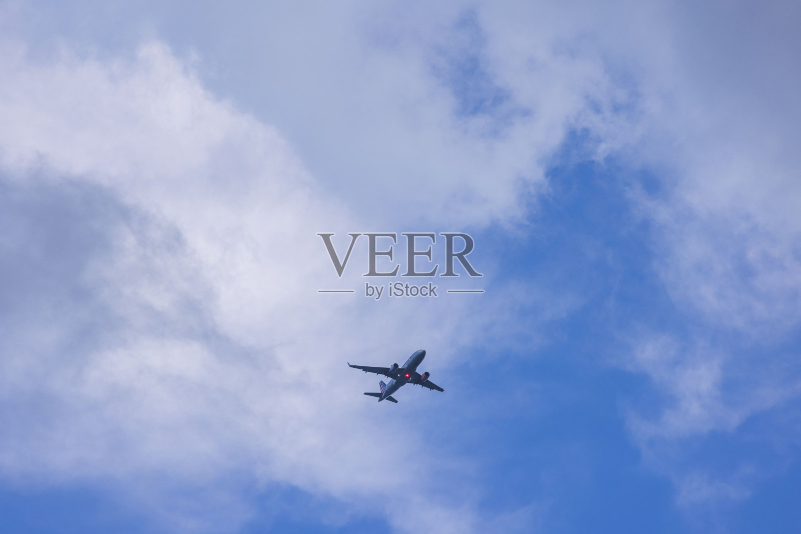 在蓝天白云的背景下，一架开着灯的着陆飞机的美丽景色。美国。照片摄影图片