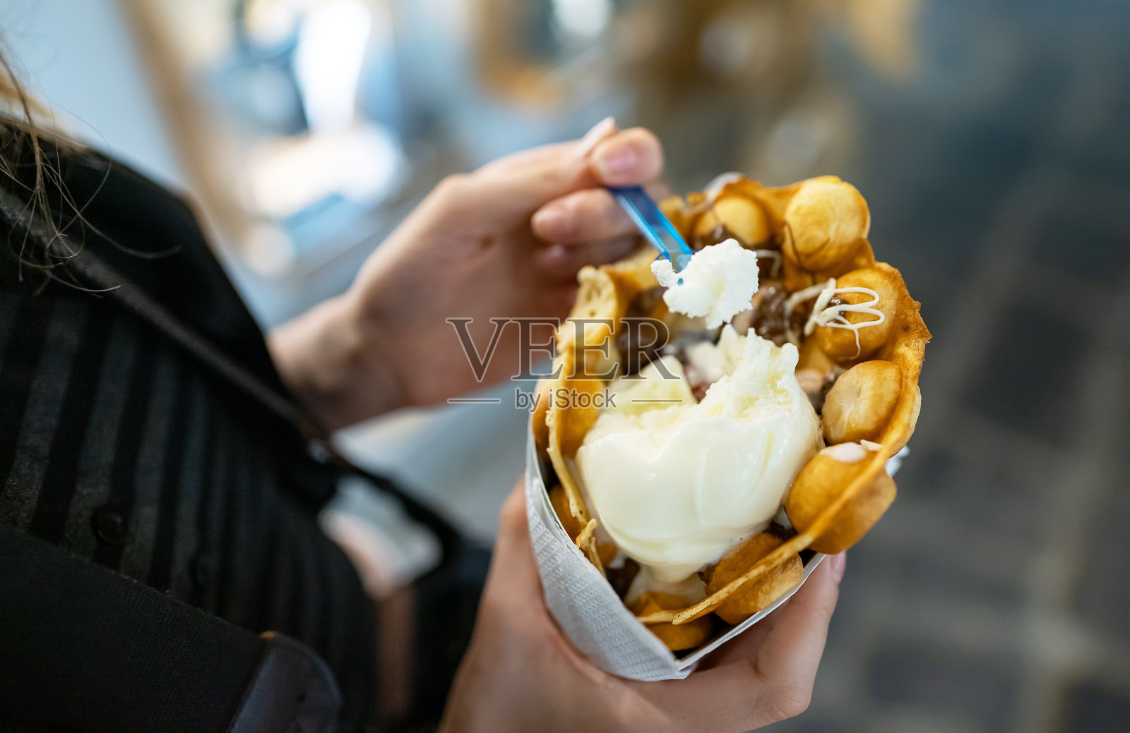 拿着华夫饼和冰淇淋的女孩。街头食品。照片摄影图片