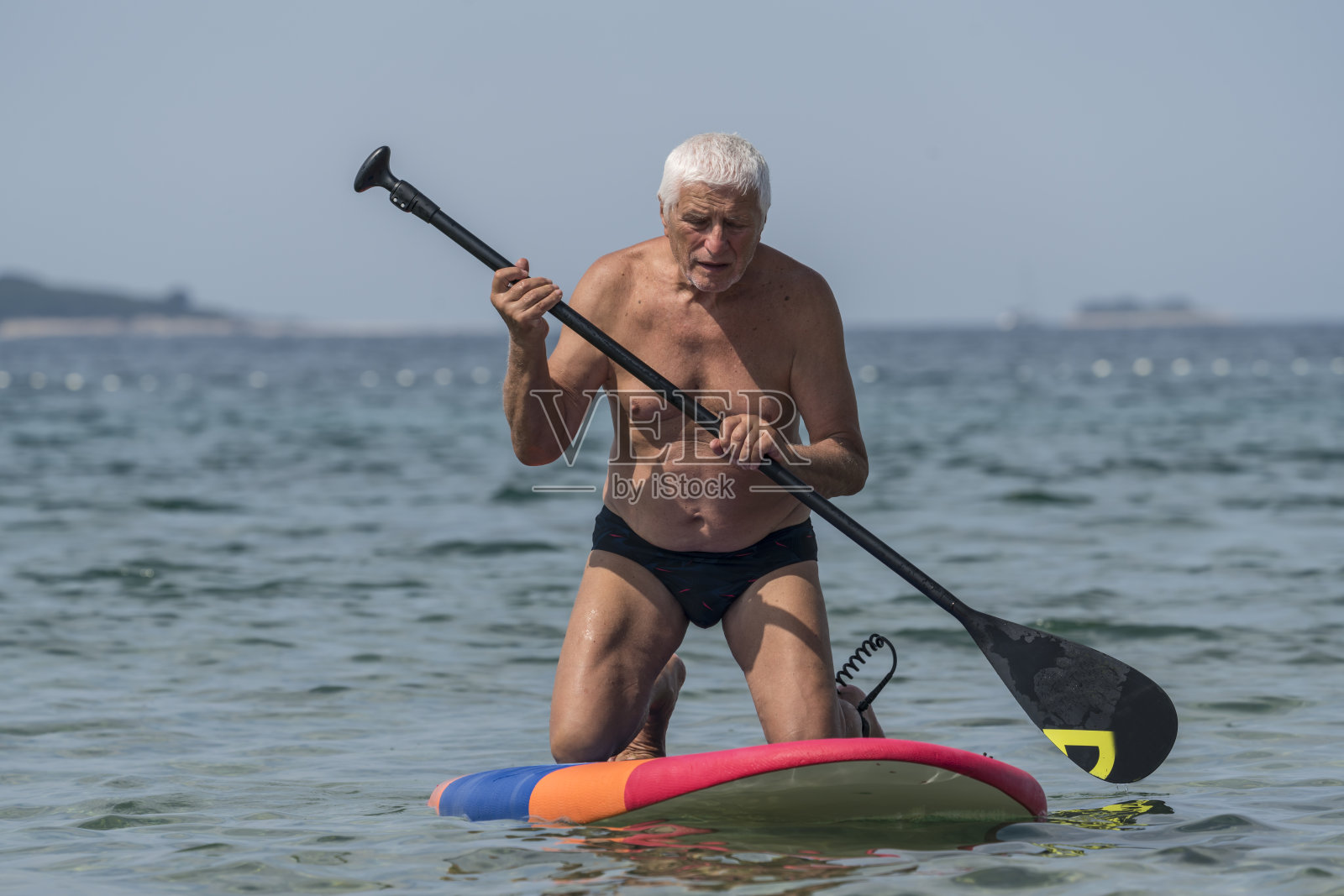 老人跪在冲浪板上照片摄影图片