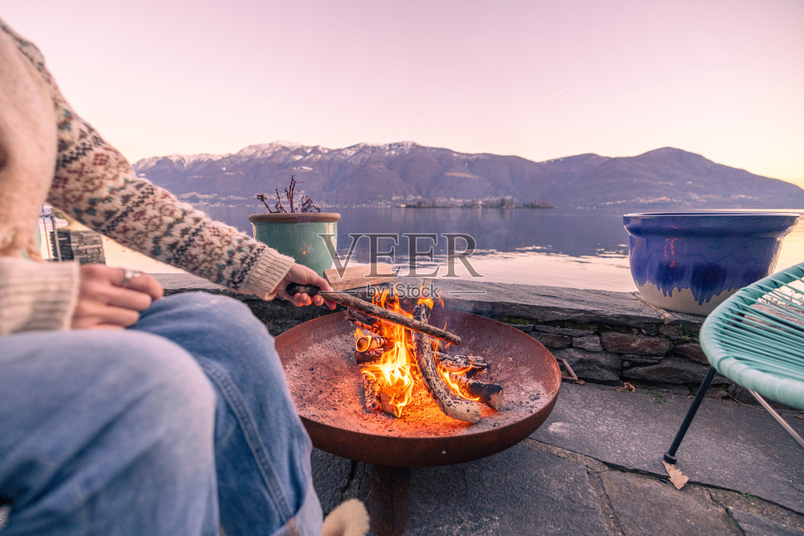 女人在她的房屋租赁中享受户外壁炉，壮丽的湖泊和山景照片摄影图片