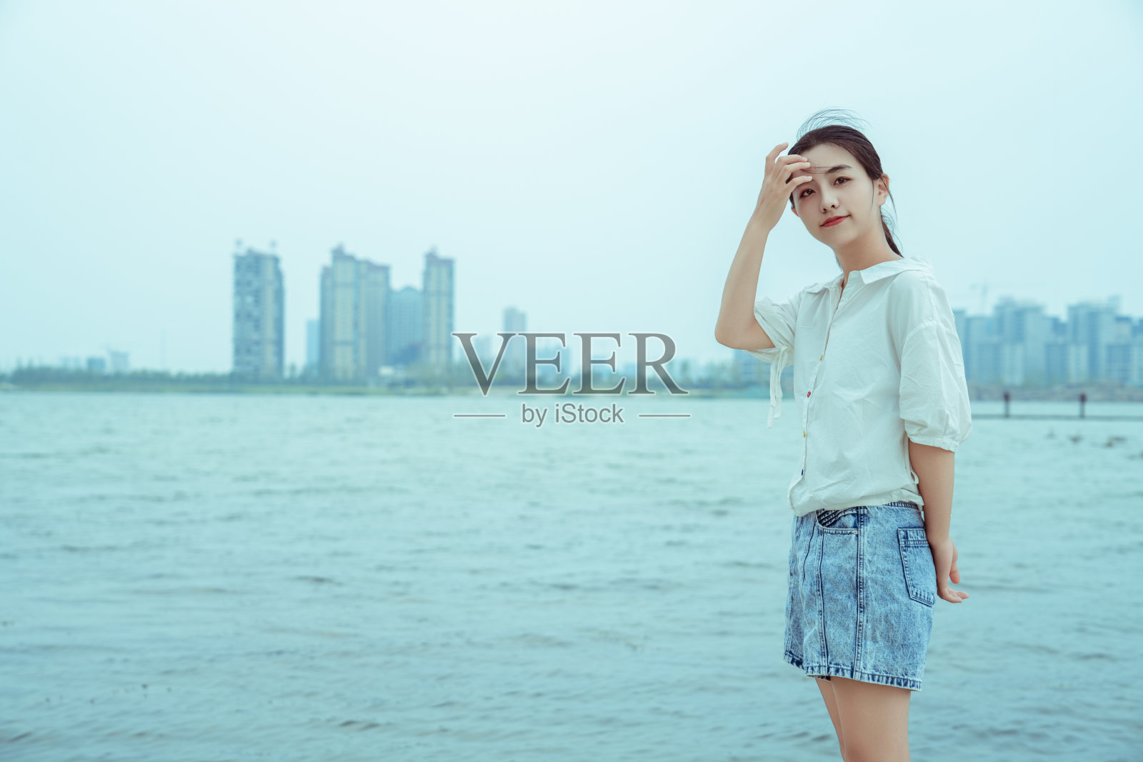 一个年轻的女孩站在湖边照片摄影图片