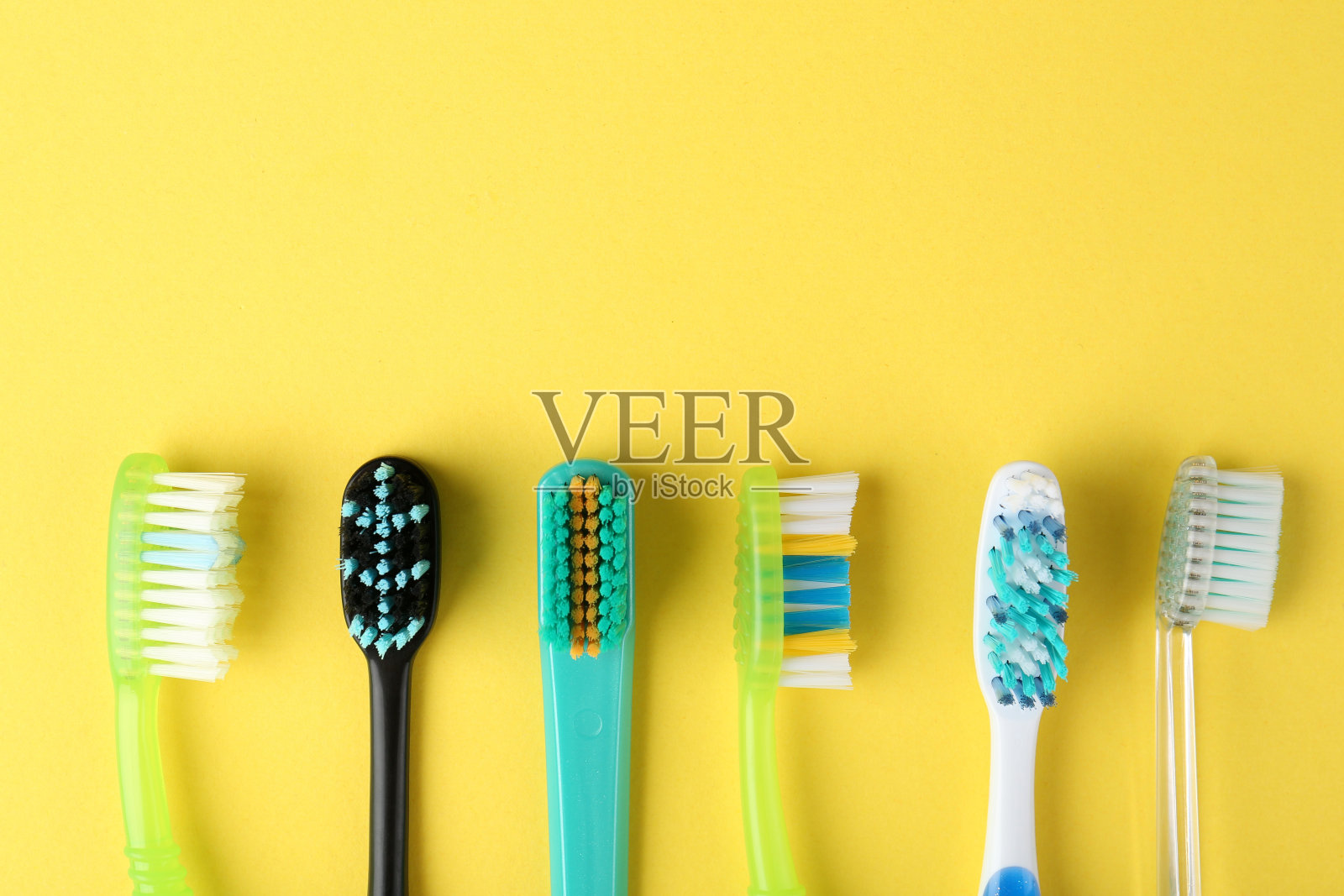 不同的牙刷在黄色背景上，平铺。文本空间照片摄影图片