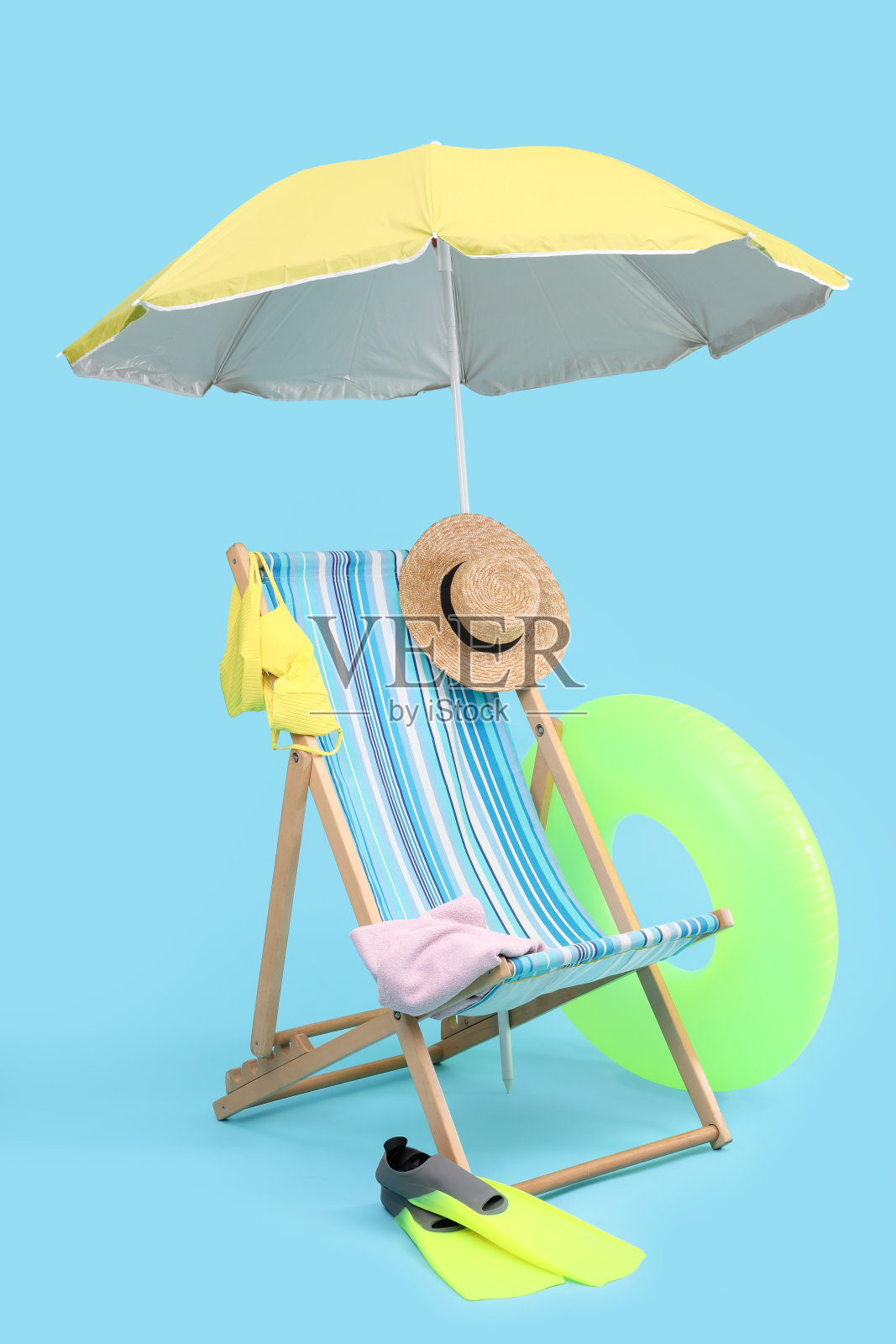 浅蓝色背景下的躺椅、雨伞和沙滩配饰。暑假照片摄影图片
