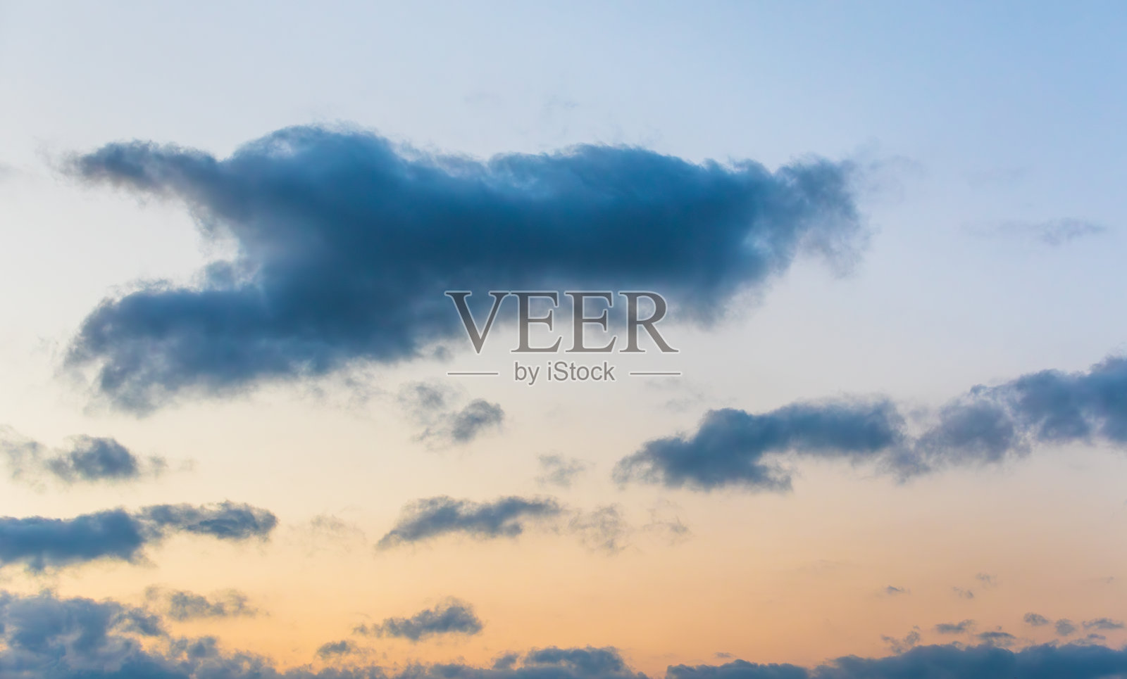 夕阳西下，橘黄色的天空中飘着深蓝色的云照片摄影图片