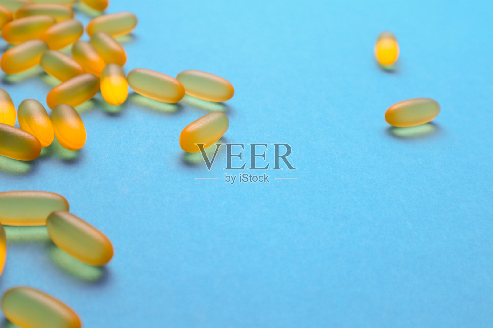 鱼油胶囊，欧米茄3，维生素e在蓝色背景与复制空间。保健、维生素、补品每日摄入的概念。照片摄影图片