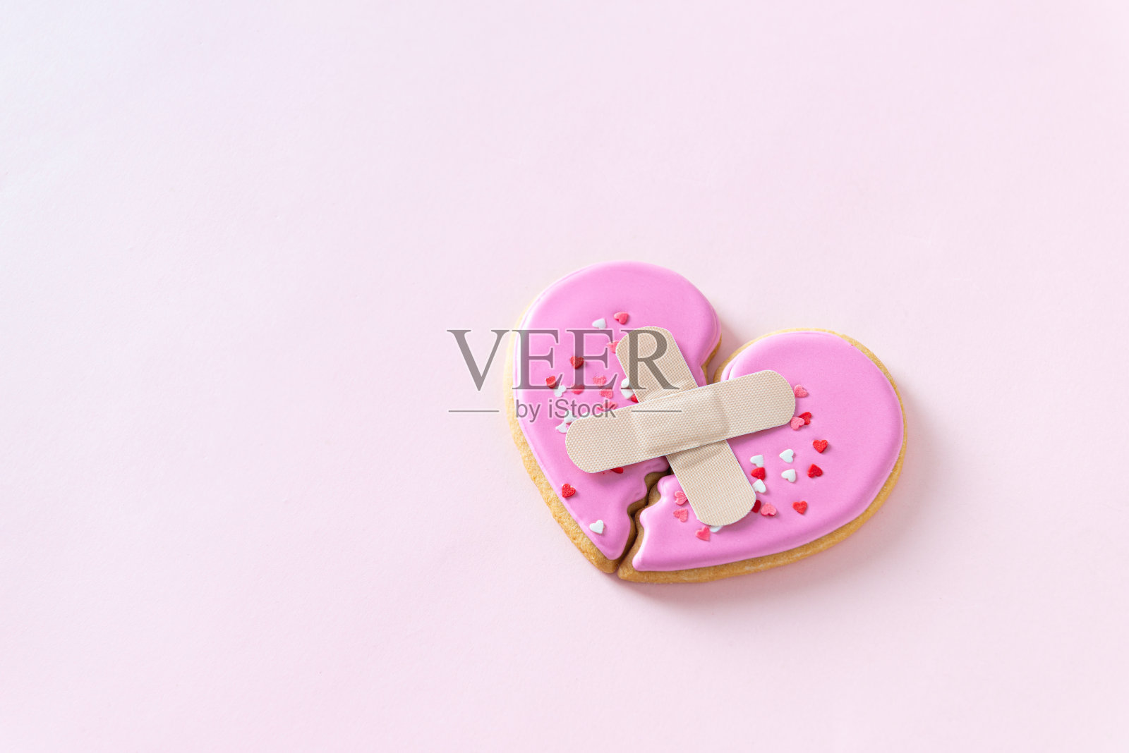 粉色背景上两半石膏心，象征分手、离婚、冲突、心理治疗，以及情感缺失照片摄影图片