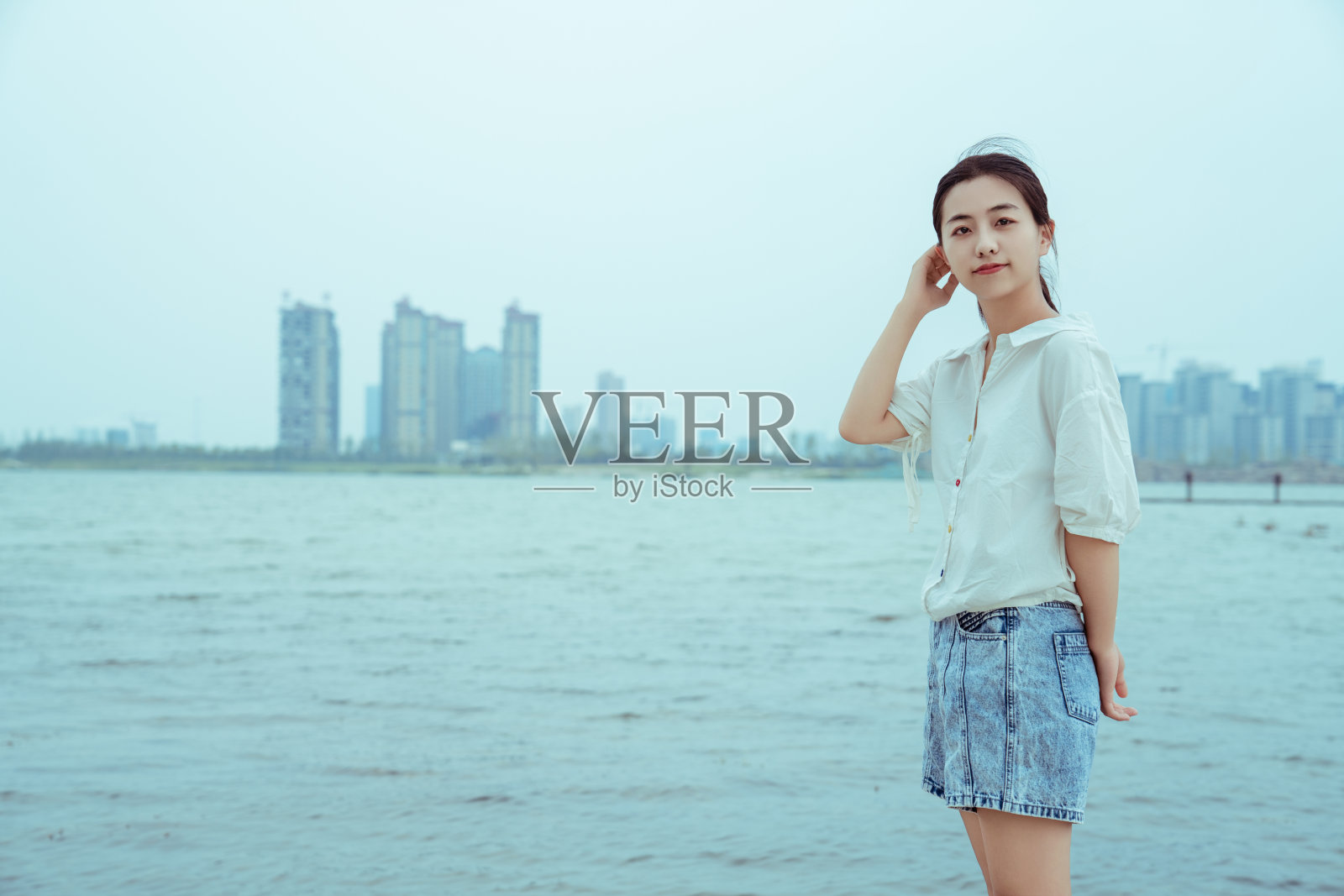 一个年轻的女孩站在湖边照片摄影图片