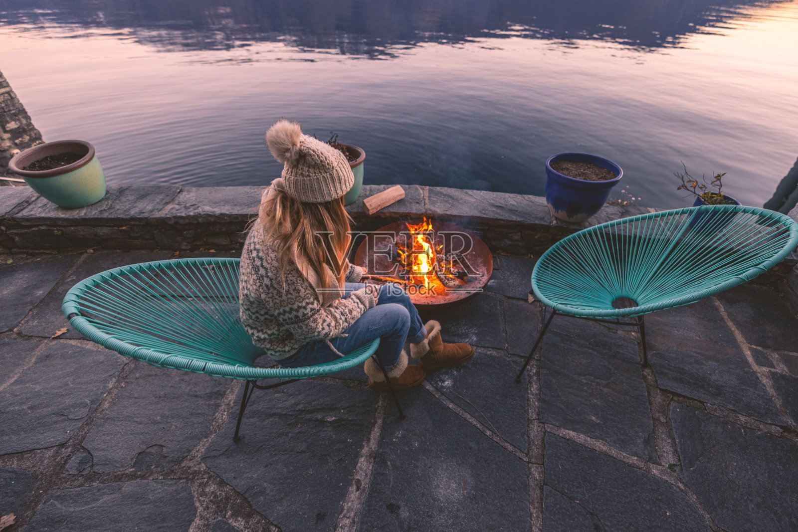 女人在她的房屋租赁中享受户外壁炉，壮丽的湖泊和山景照片摄影图片