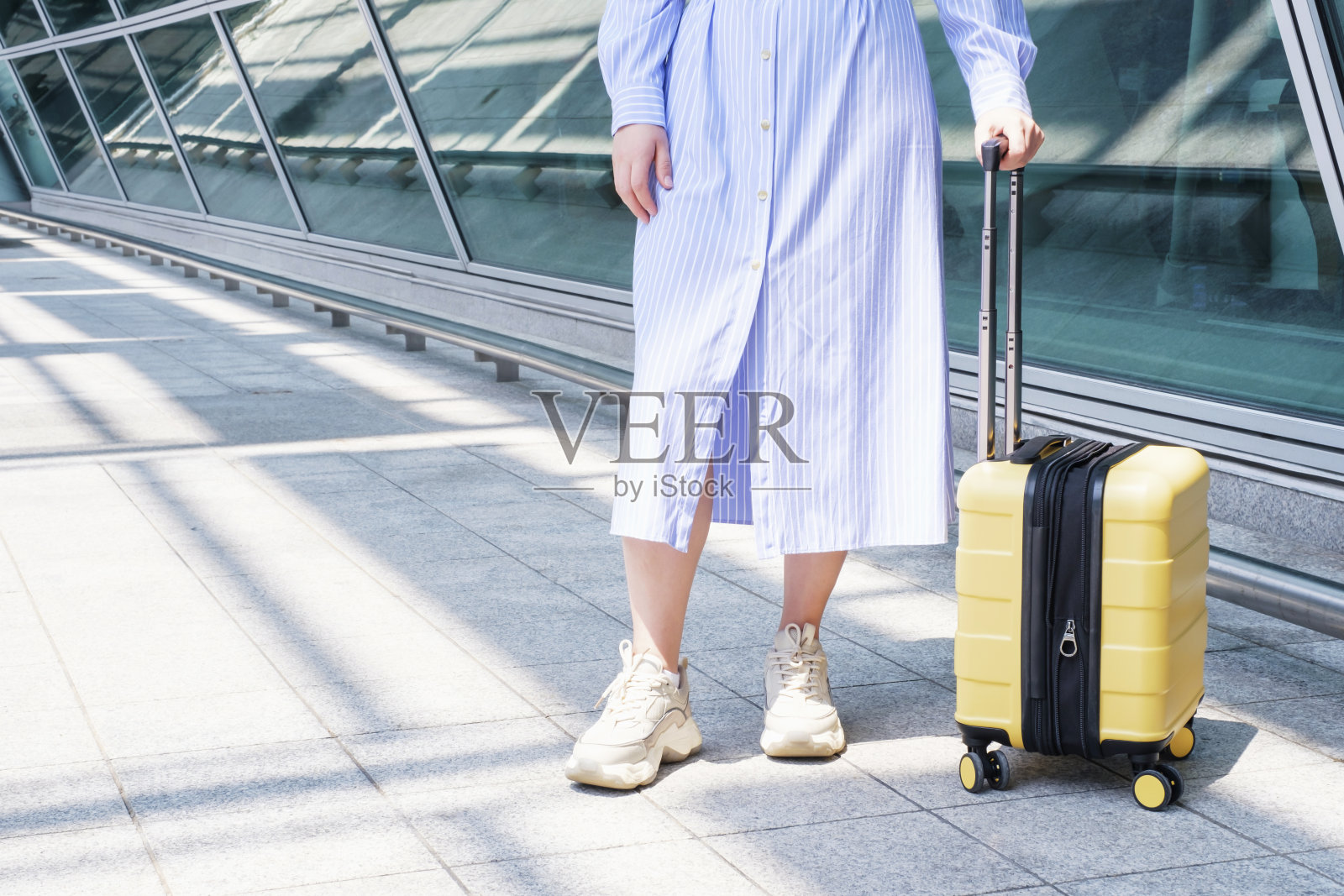 机场附近的年轻女子带着黄色行李箱，旅行的概念。照片摄影图片