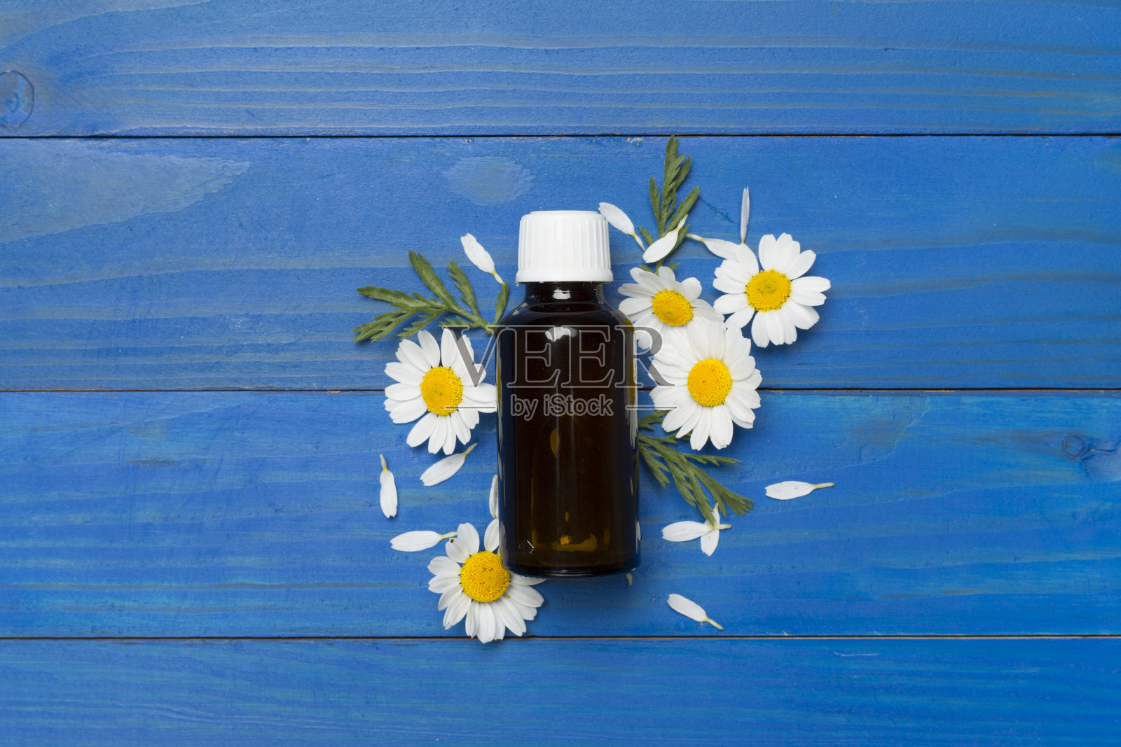 瓶子与洋甘菊精油和花在木制背景，顶视图照片摄影图片