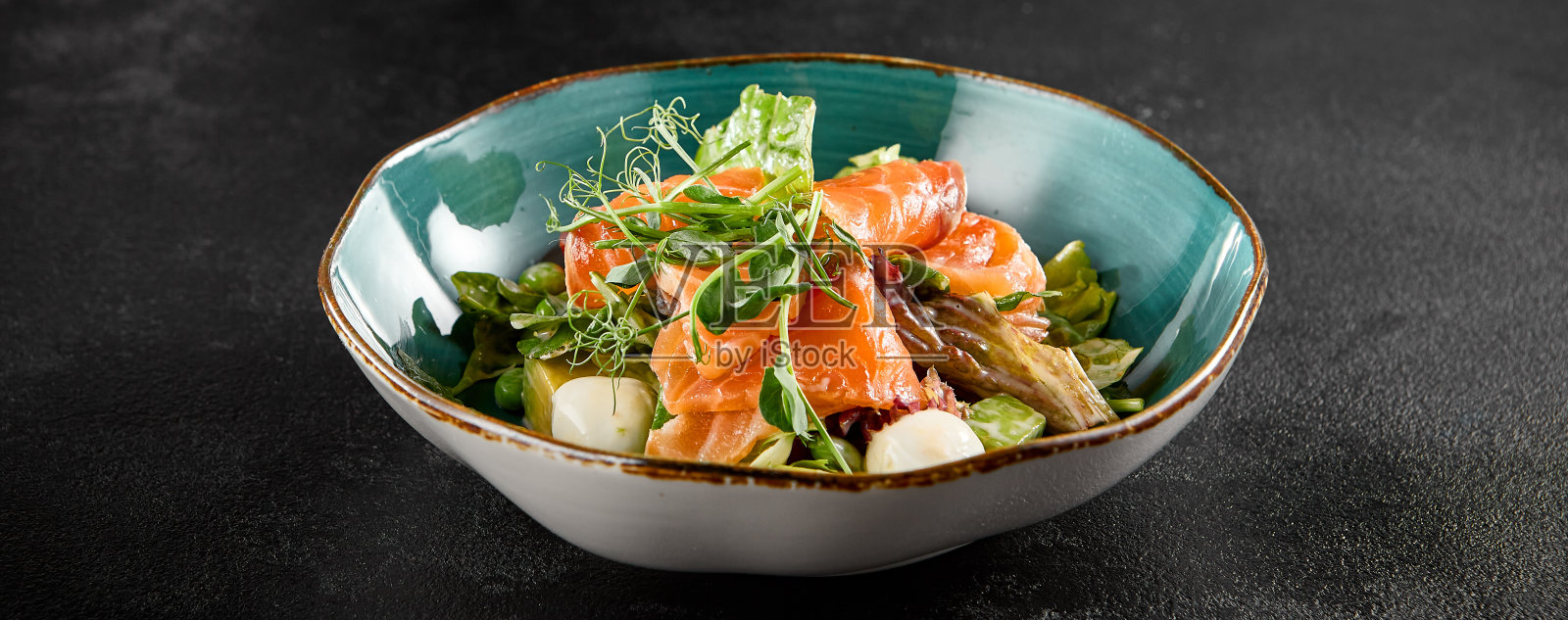 三文鱼沙拉，马苏里拉奶酪，鳄梨，在一个绿松石陶瓷碗照片摄影图片
