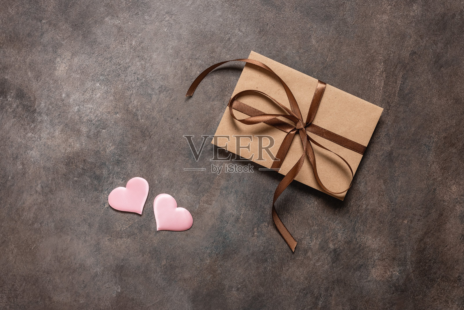 棕色信封系着丝带和粉红色的丝心在一个黑暗的复古背景。情人节贺卡。俯视图，平面布局，复制空间。照片摄影图片