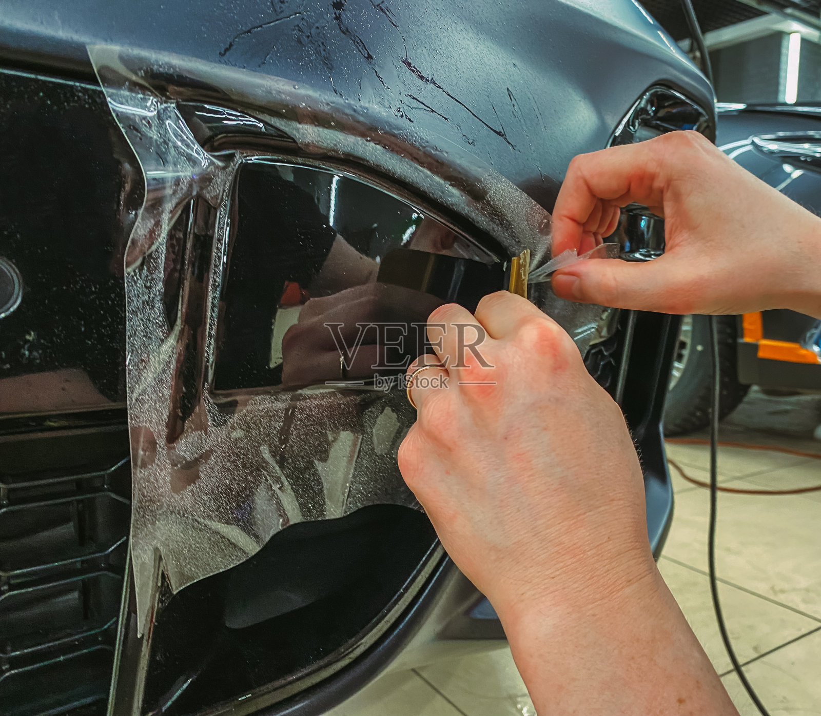 汽车包装。汽车包装专家将聚氨酯薄膜涂在汽车上。有选择性的重点。PPF保护膜，防止碎片和划伤。照片摄影图片