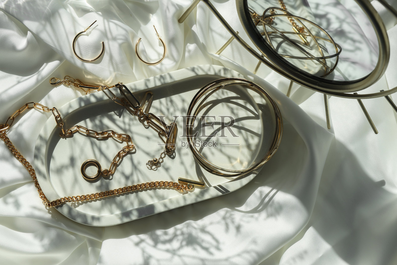 金属链条等不同配件在白色织物上平铺。奢华的珠宝照片摄影图片