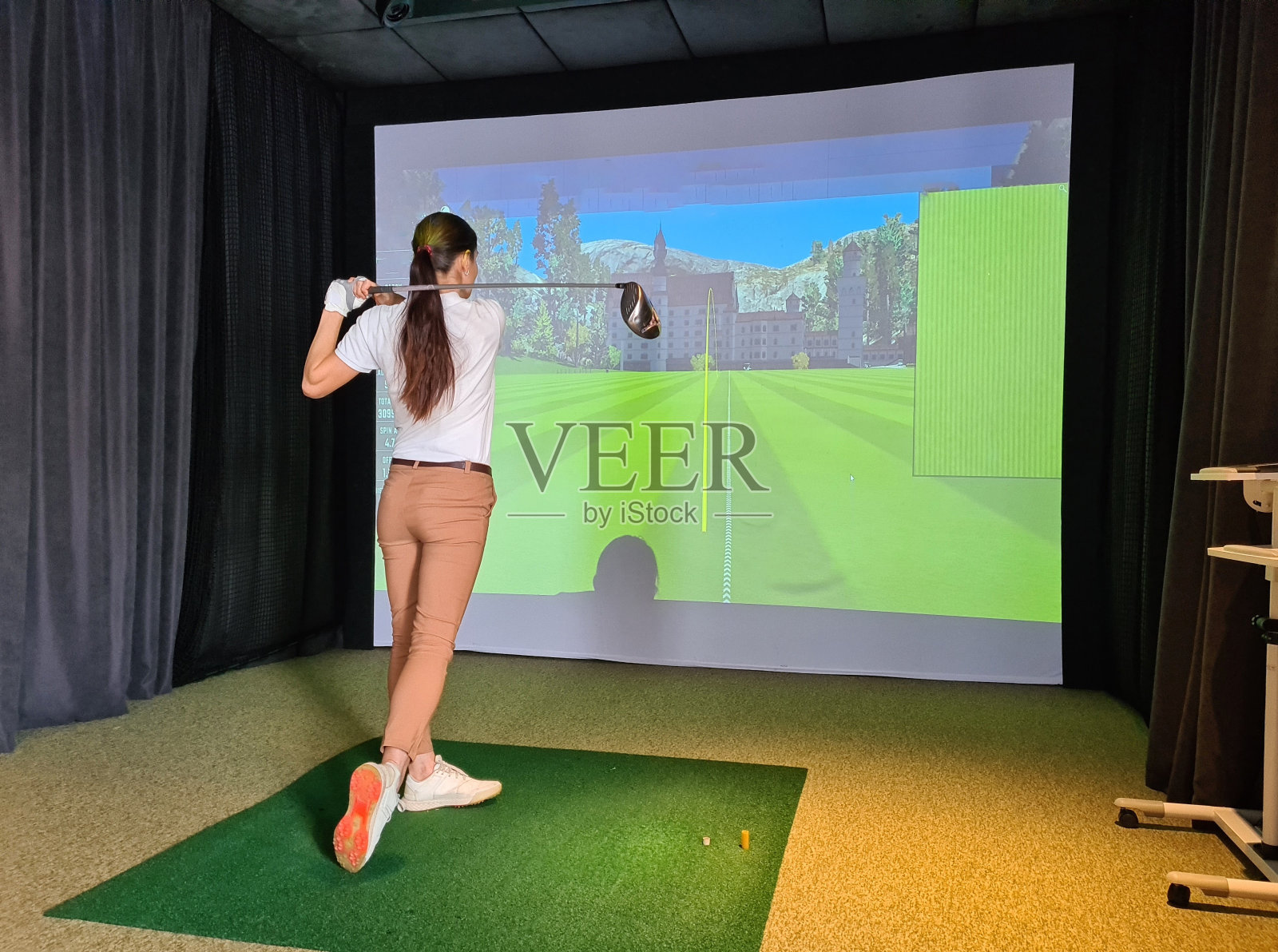 女高尔夫球手在高尔夫模拟器上打高尔夫球照片摄影图片