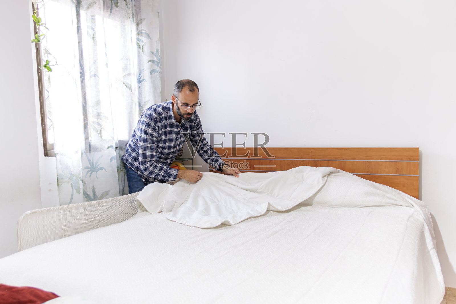 做家务的年轻人。整理床铺。照片摄影图片