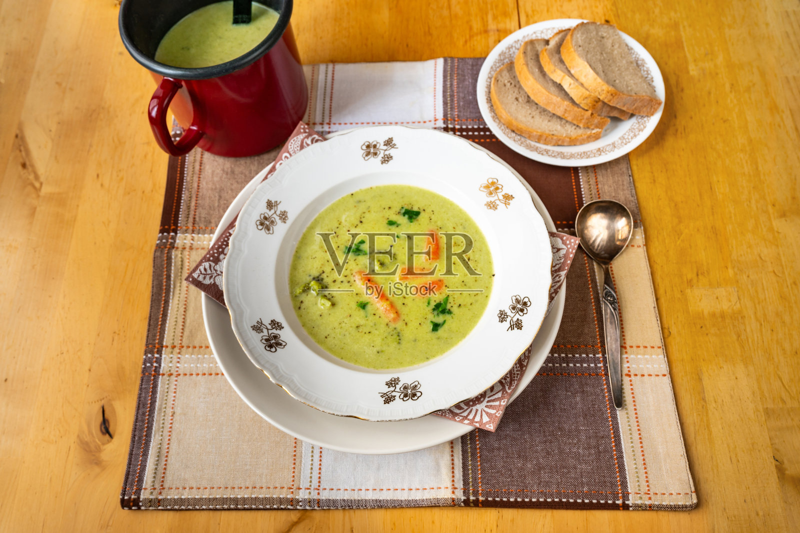 奶油花椰菜汤在盘子和锅，长柄勺，切片面包。照片摄影图片