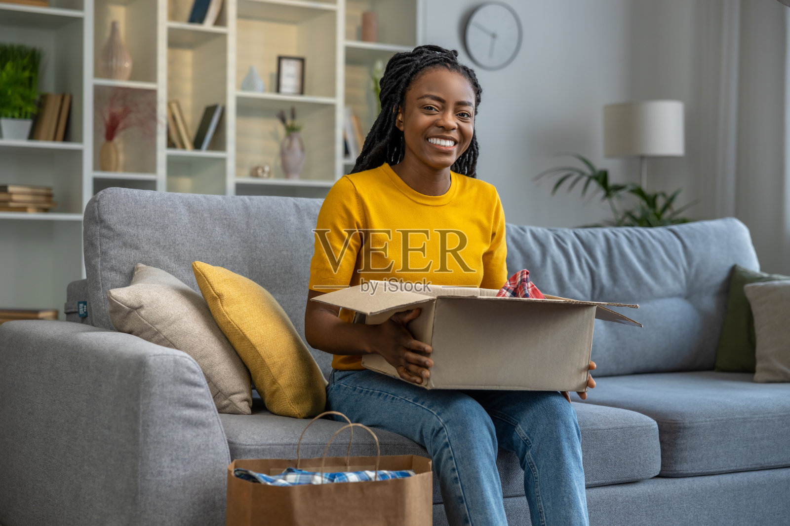 微笑和幸福的女人看起来满足，打开一个盒子的衣服照片摄影图片