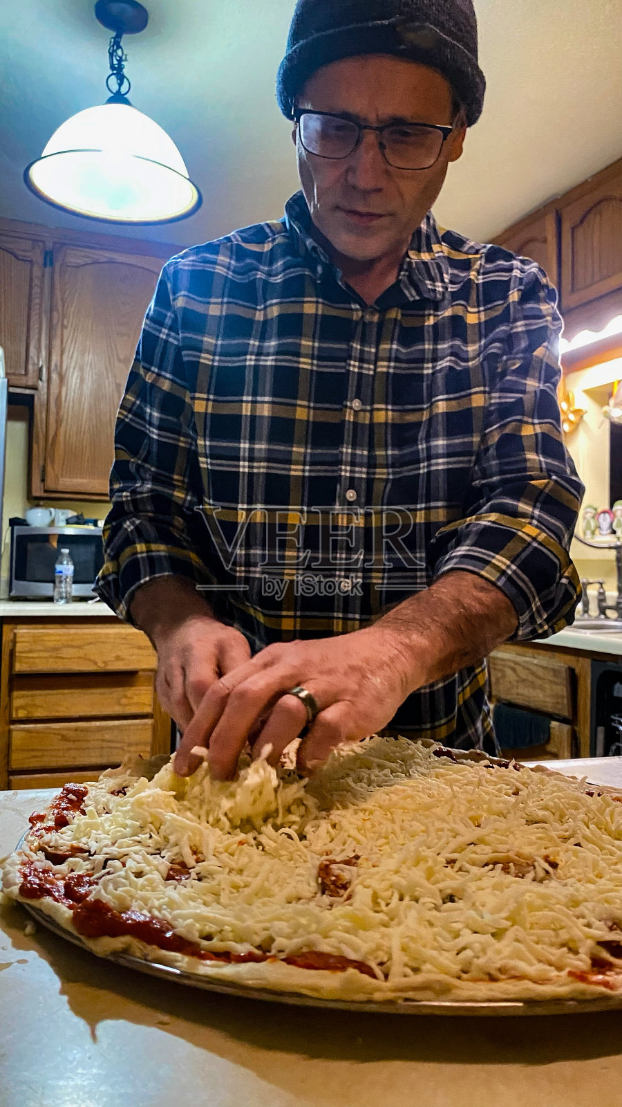 一位老人正在为他的家人做健康的自制披萨照片摄影图片