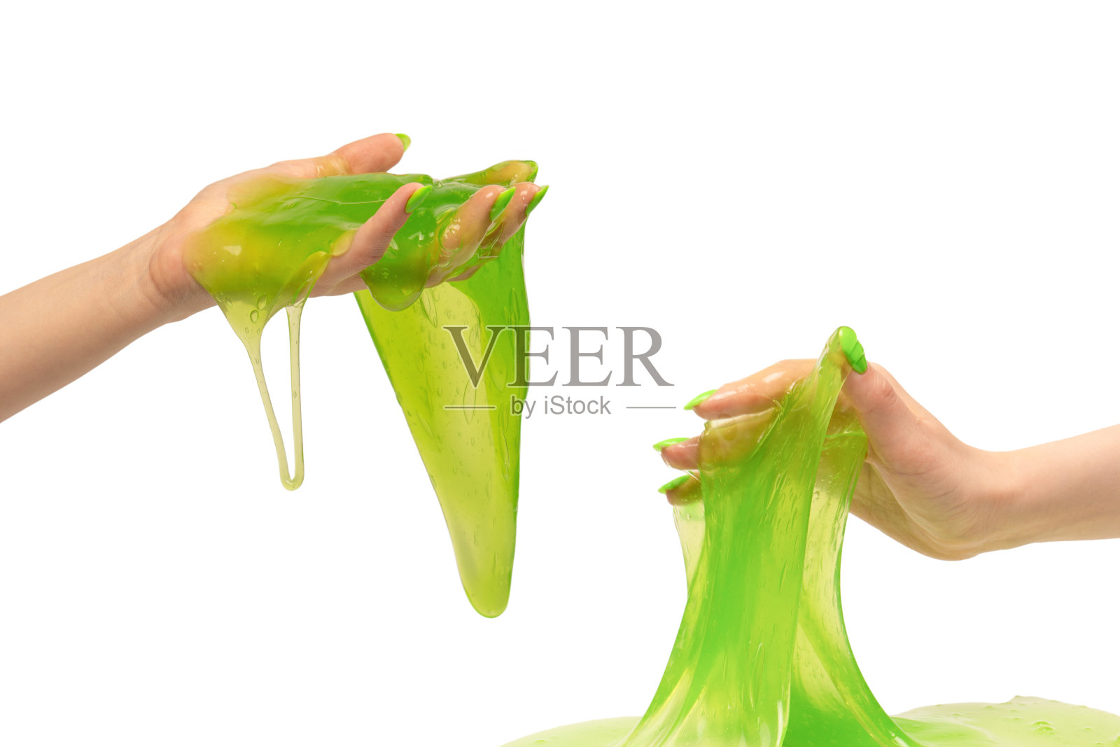 女人手里拿着绿色黏液玩具，白色背景上有绿色的指甲。照片摄影图片