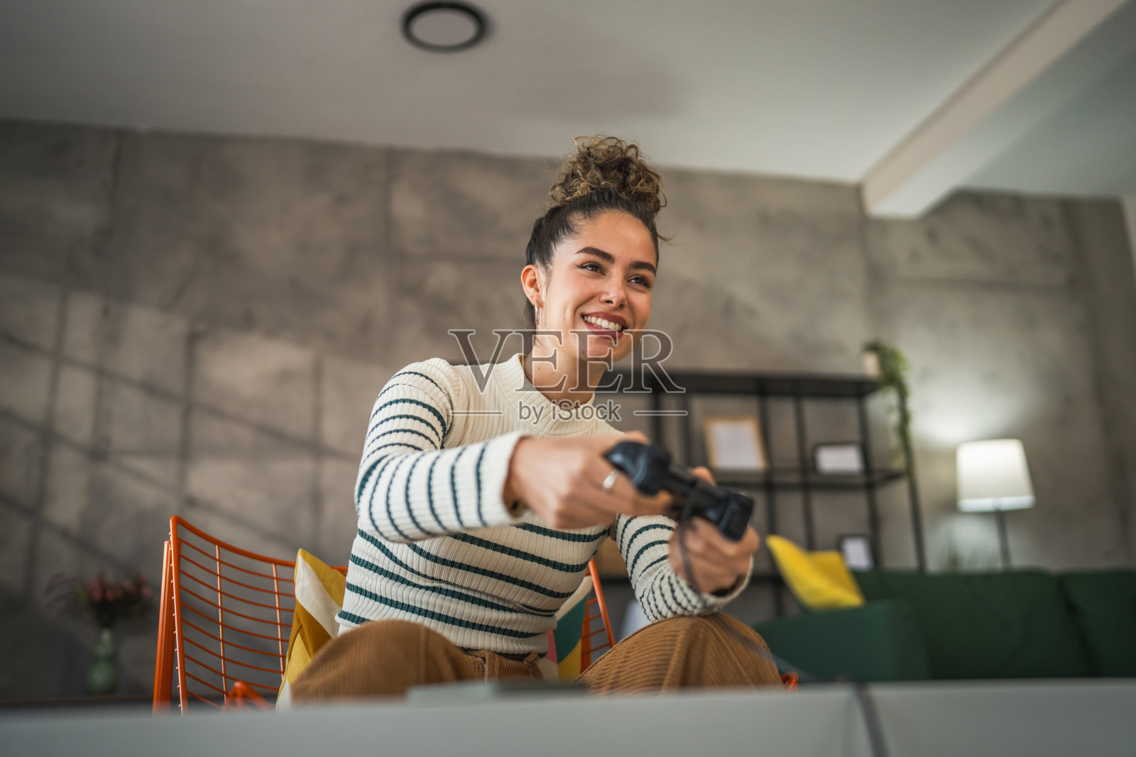 一名年轻女子在家里拿着操纵杆玩游戏机照片摄影图片