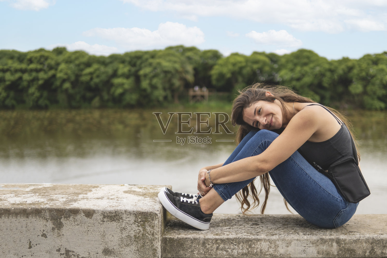 年轻女子坐在海边看着镜头照片摄影图片