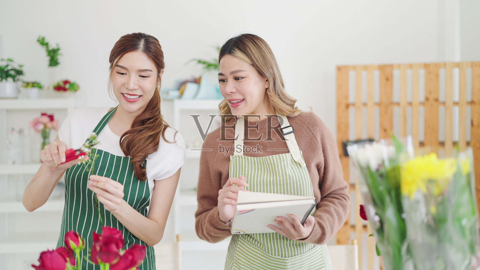 花店的亚洲女老板教实习生如何在花店制作花卉构图。两个花匠正在把鲜花插花。小型企业概念照片摄影图片