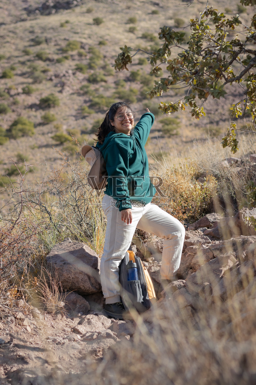一名女子沿着小路散步，微笑着指着一座墨西哥山峰的顶峰照片摄影图片