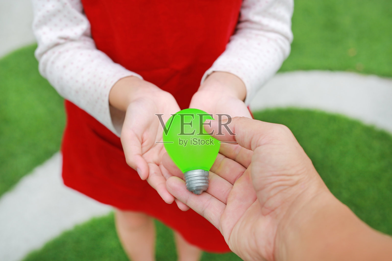 特写:人们在花园里给小女孩一个玩具灯泡。热爱地球的观念。照片摄影图片