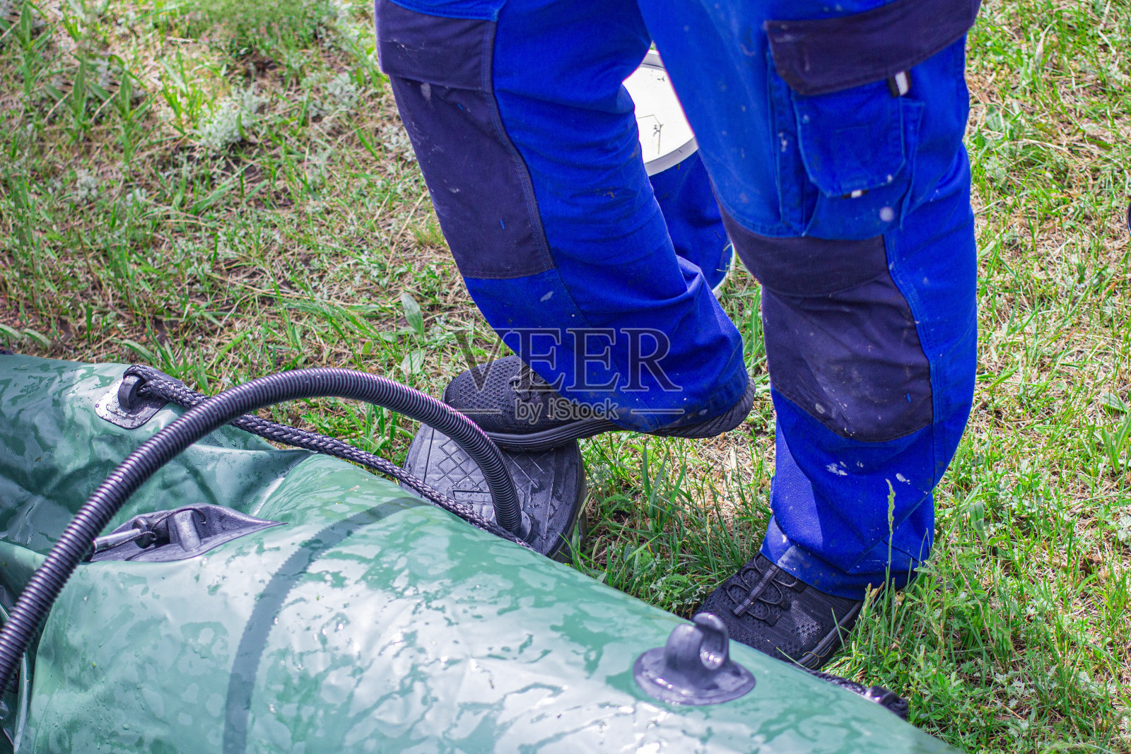 一名男子用手电动泵给橡皮艇充气(特写)，前面和背景用散景效果模糊照片摄影图片