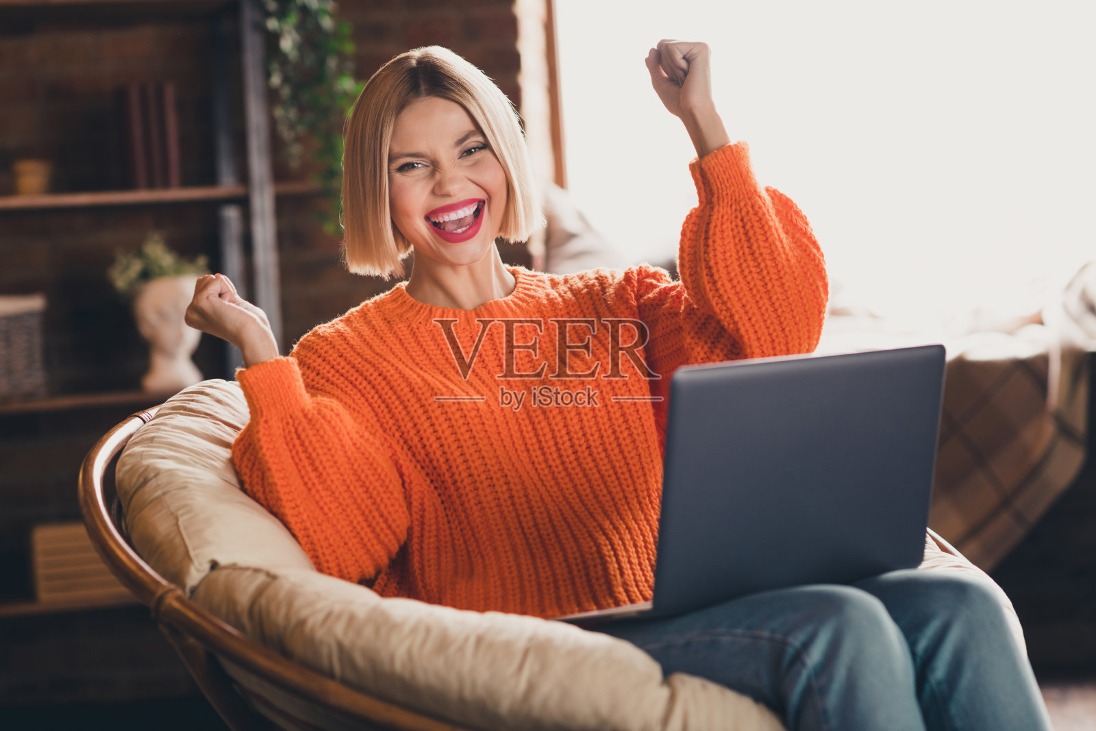 疯狂有趣的人的肖像坐在扶手椅上使用笔记本电脑举起拳头完成客厅房子室内照片摄影图片