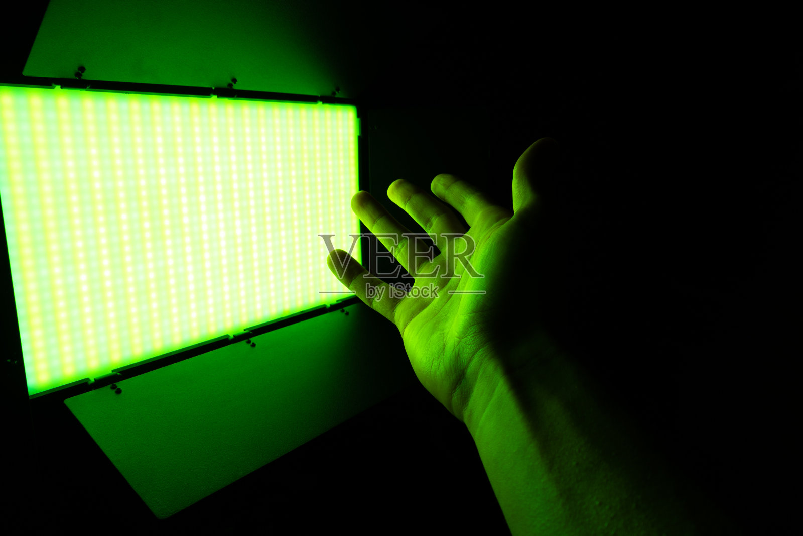 绿色霓虹灯。专业的照片或视频照明。SRGB led面板上的三脚架为家庭或工作室拍摄。调整照明设备。照片摄影图片