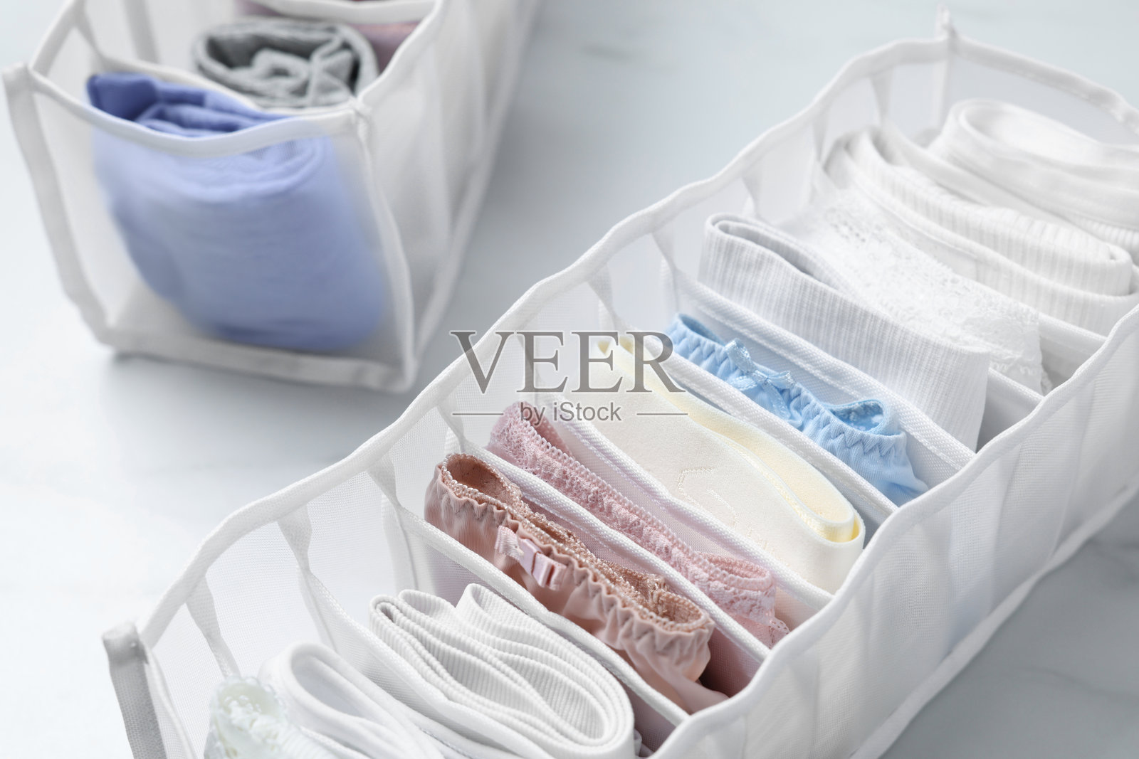 白色大理石桌上摆放着折叠好的女性内衣的组织者，特写照片摄影图片