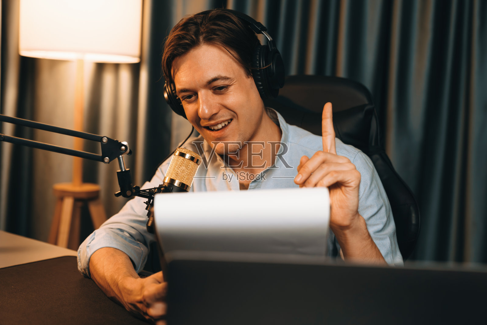 播音员在夜晚温暖的灯光下向听众朗读剧本。金钱。照片摄影图片