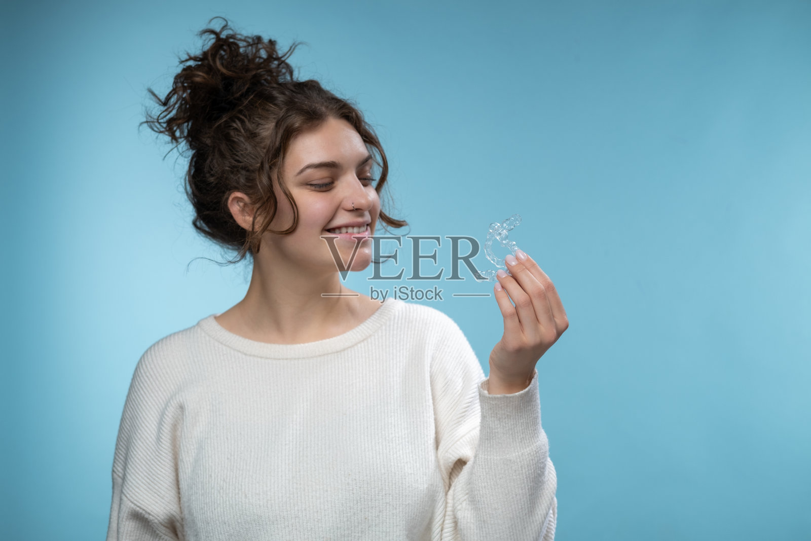 一位女士拿着隐形牙齿矫正器。照片摄影图片