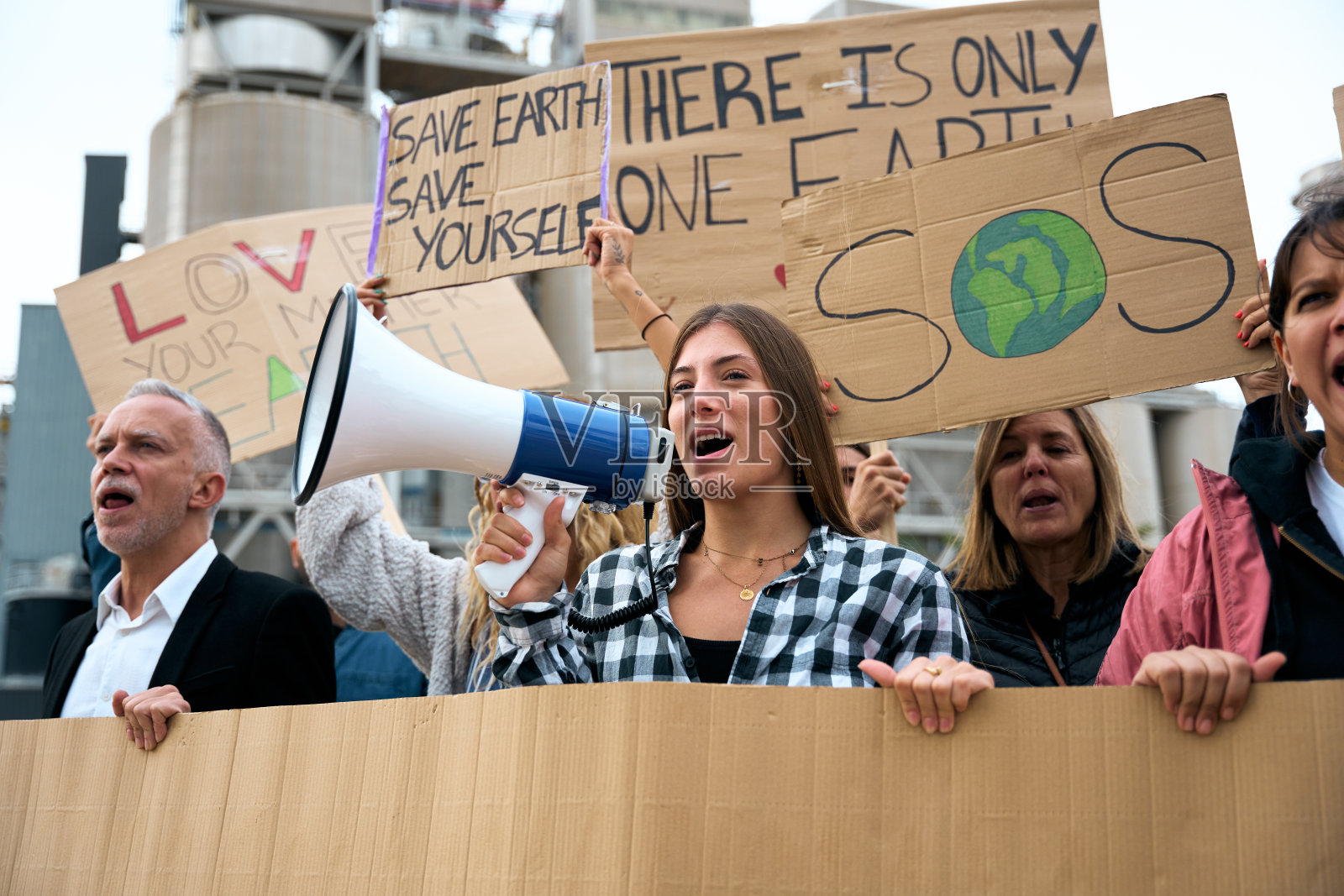 一名妇女在示威中拿着扩音器大喊大叫。人们在气候变化大会上照片摄影图片