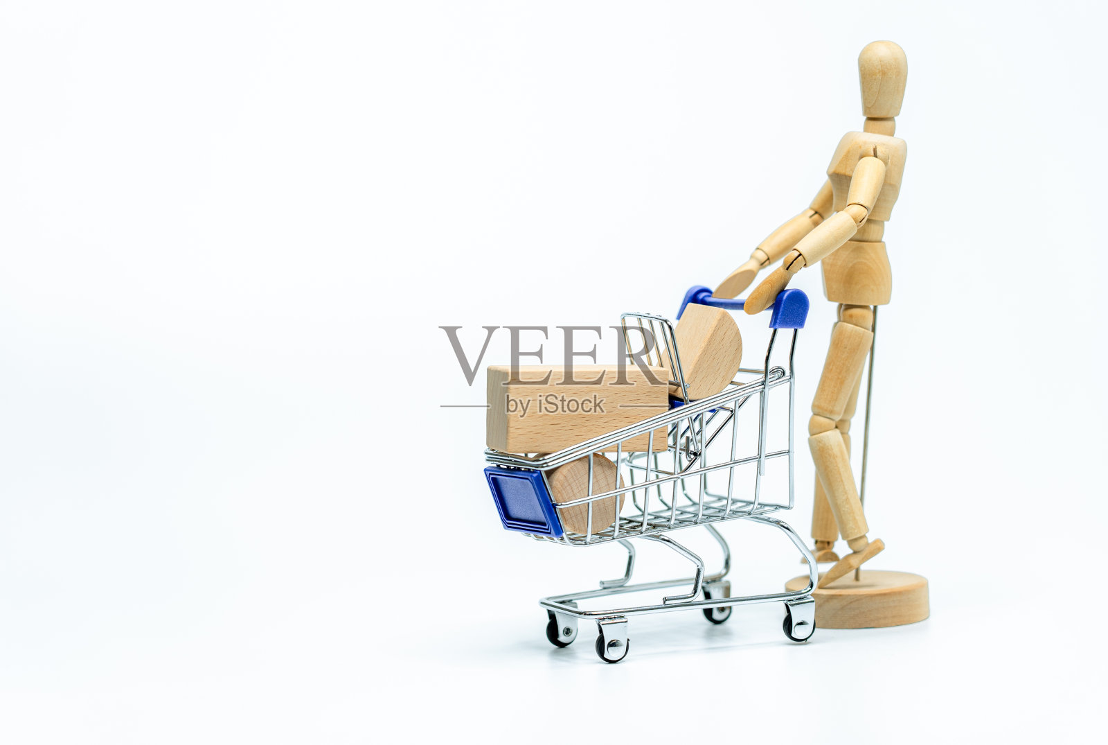 木制娃娃与购物车在白色背景。商业或创意概念照片摄影图片