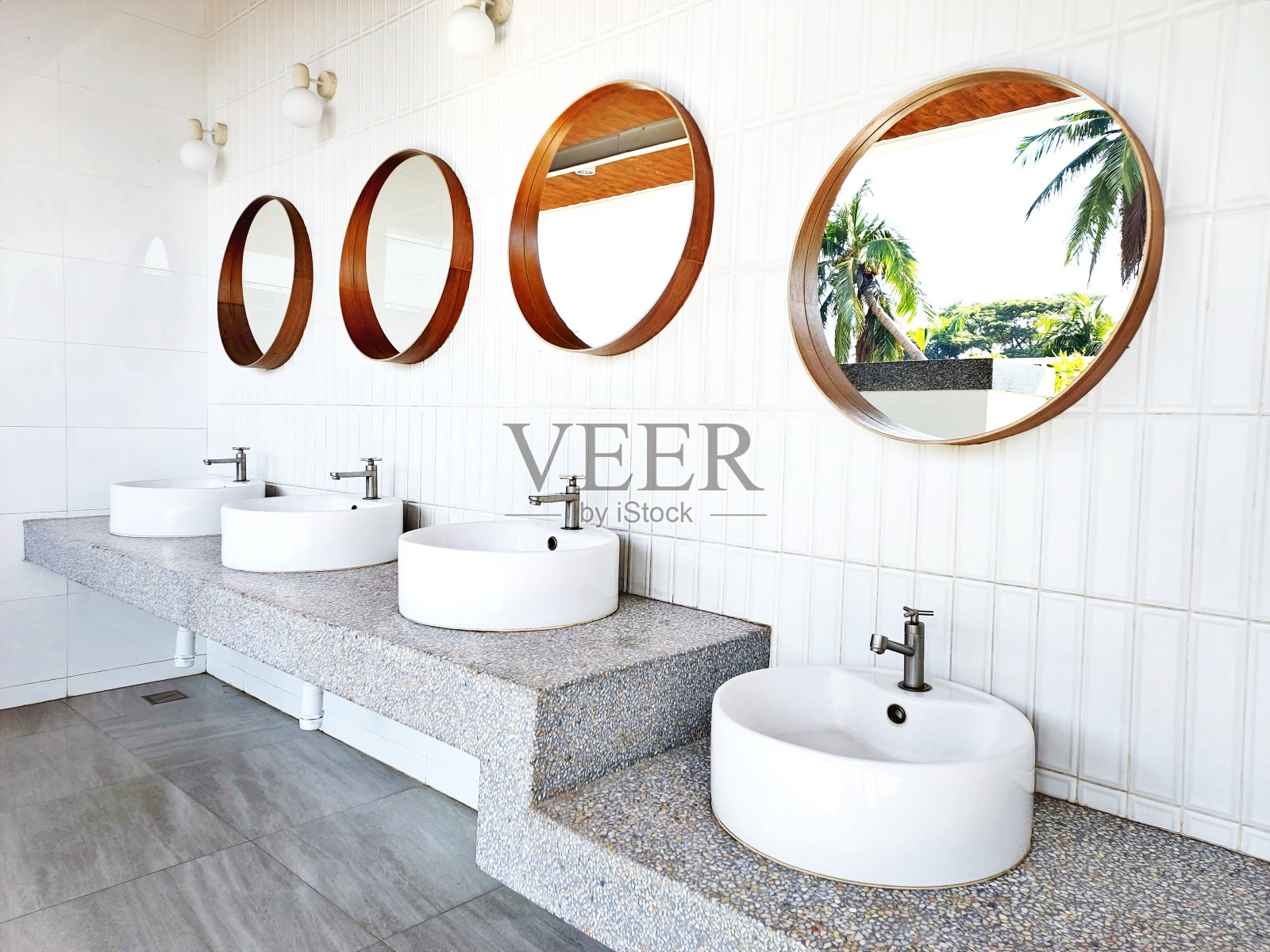 户外卫生间设计陶瓷墙上的圆形镜子，花岗岩架子上的白色洗手盆照片摄影图片