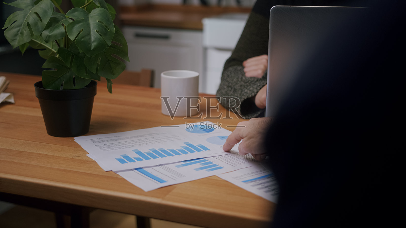 一个男人坐在一个现代化的厨房里，和他对面的人说话，给他看她的讲义照片摄影图片