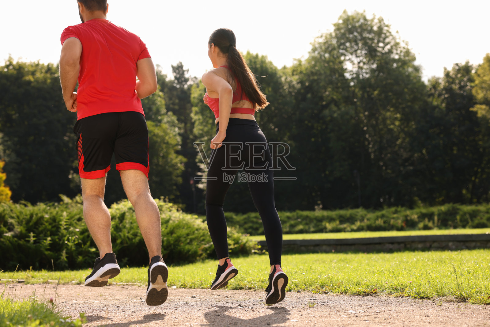 健康的生活方式。一对情侣在阳光明媚的日子里在公园里跑步，从低角度看。文本空间照片摄影图片