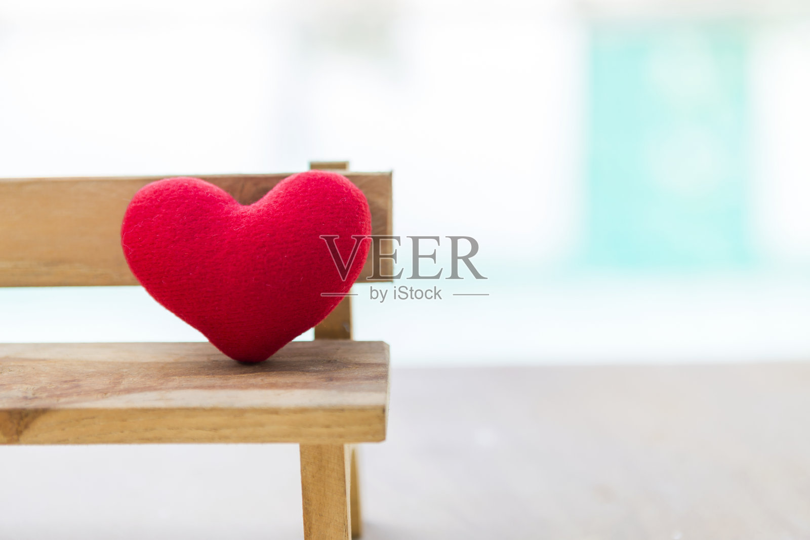 模糊背景中木椅上的红色爱心特写照片摄影图片
