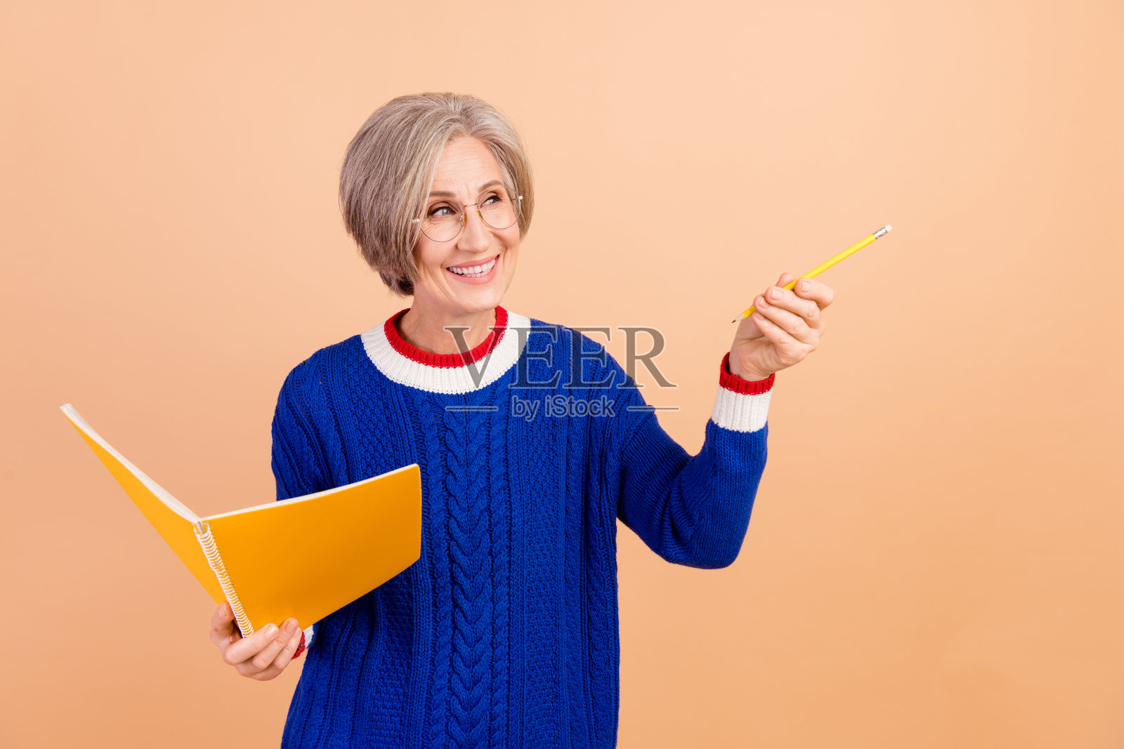 迷人的退休女士穿着蓝色时尚的衣服，在米色的背景上呈现出漂亮的空白空间照片摄影图片