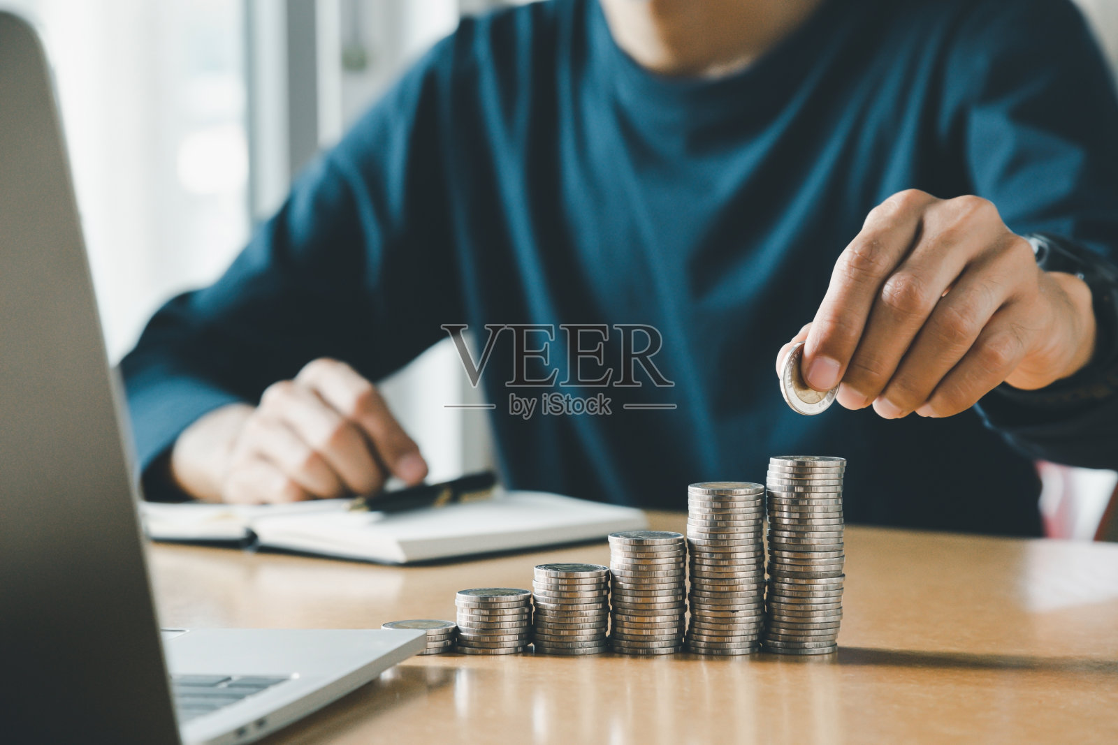 手把硬币放在存钱罐里存钱和省钱的概念。照片摄影图片